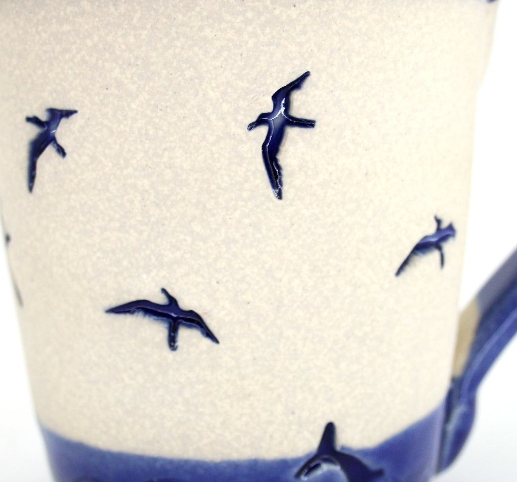 Coastal themed pottery, high fired stoneware mug with a hand etched design of gulls diving into the water. Close up of artwork