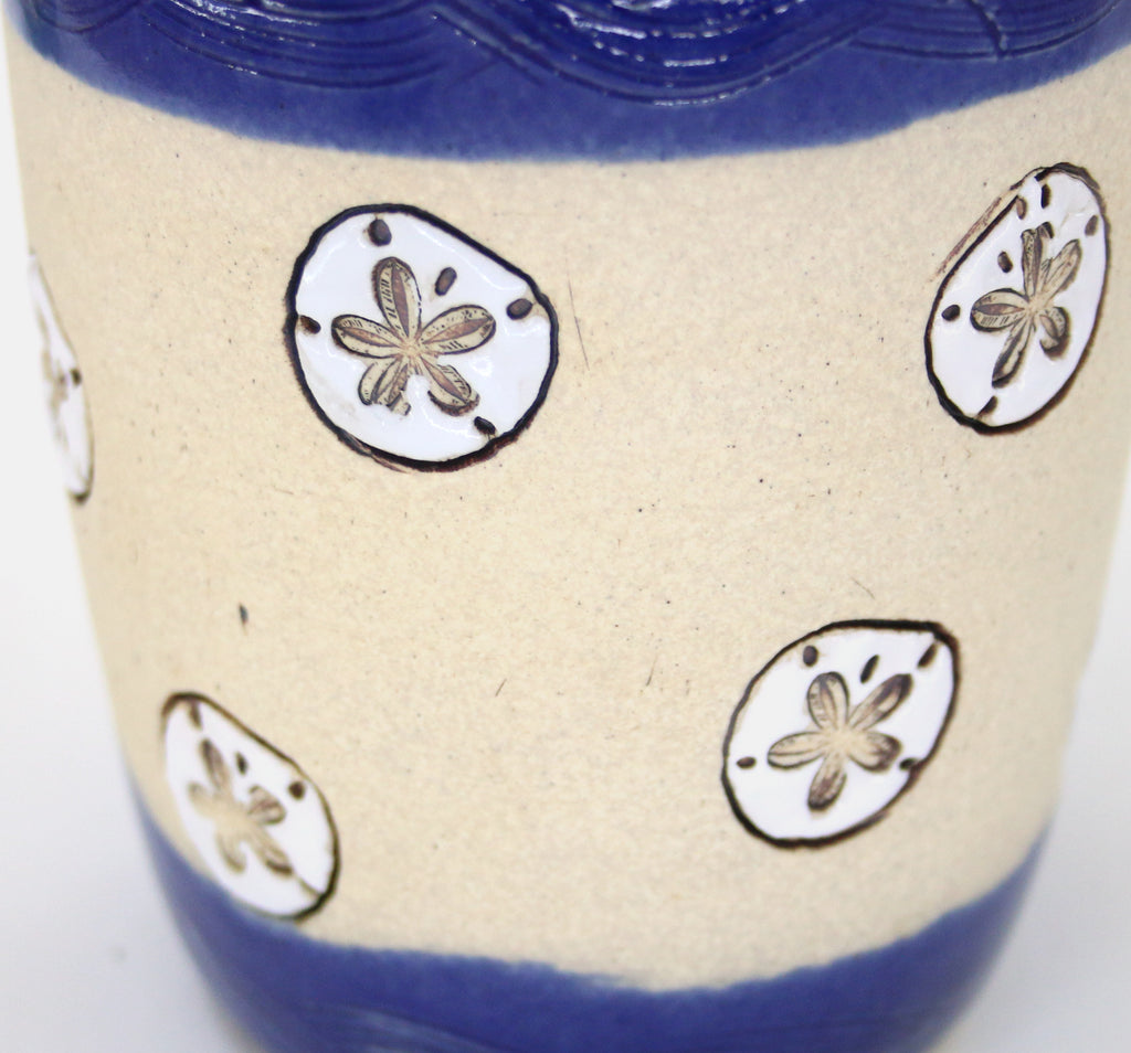 Coastal themed stoneware mug in Caribbean Blue with hand carved sand dollar design. Close up detail.