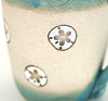 Coastal themed stoneware mug in Caribbean Blue with hand carved sand dollar design. Close up detail.