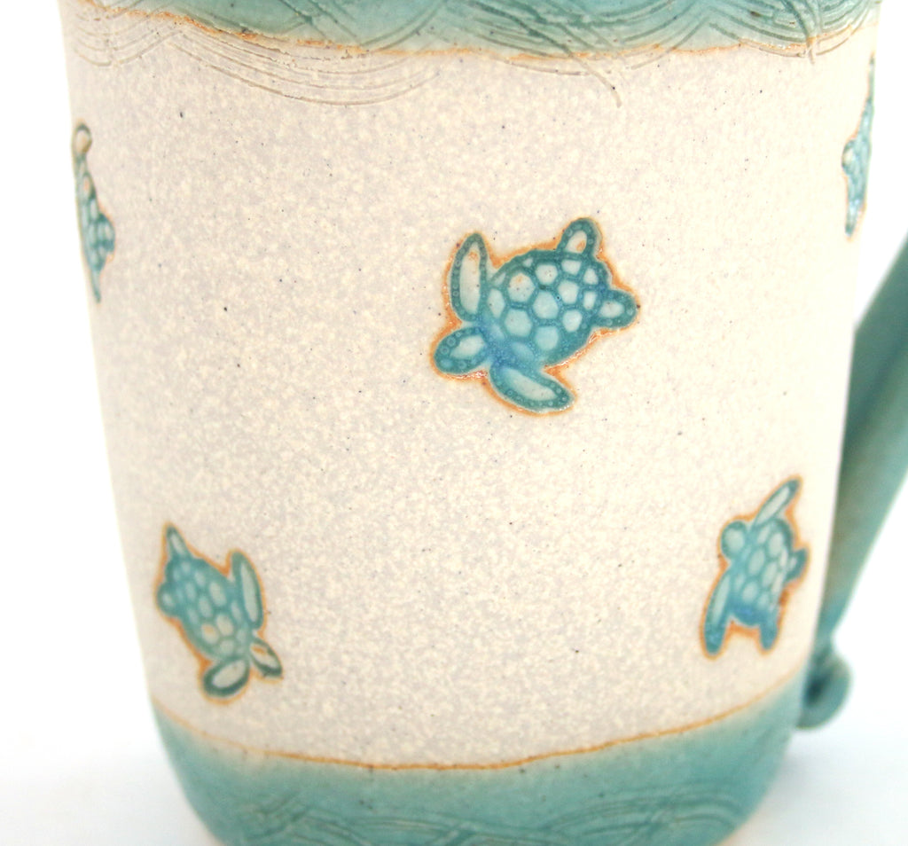 Coastal themed pottery, high fired stoneware mug with a hand etched design of sea turtles. Close up detail.