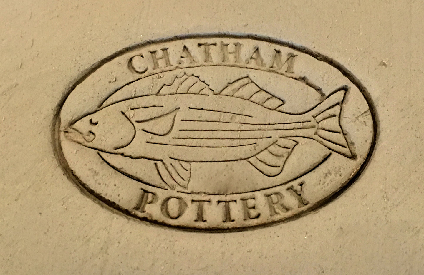 The Chatham Pottery logo with a striped bass surrounded by the words Chatham Pottery stamped in clay